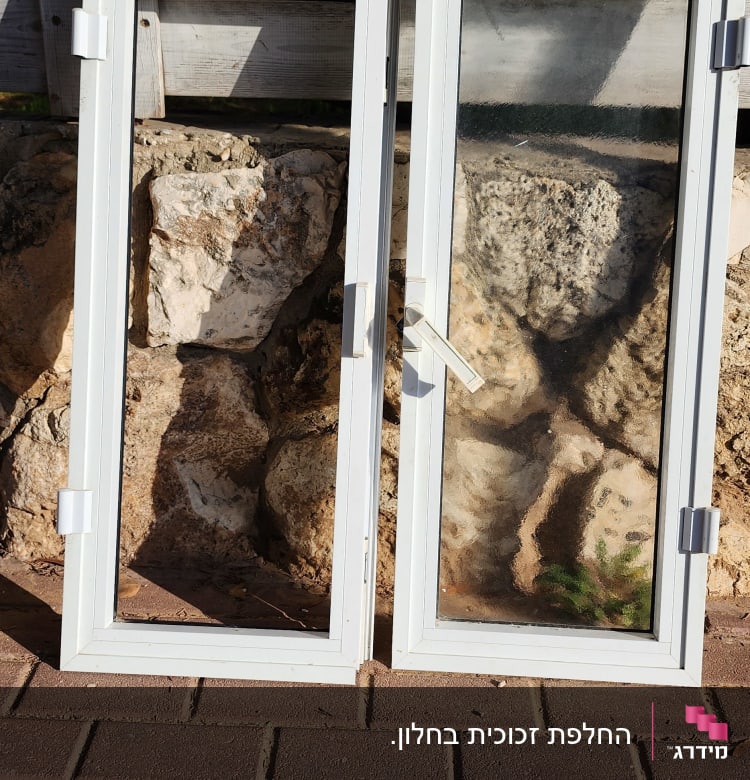 שני חלונות זכוכית עם מסגרת לבנה על רקע קיר עץ